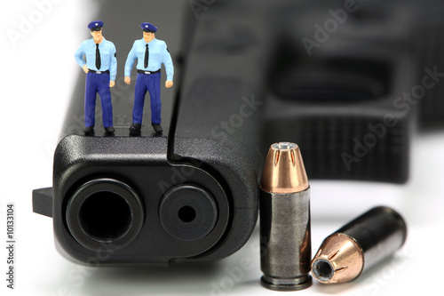 Miniature policemen standing on a gun with bullets