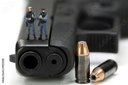 Miniature SWAT team standing on a gun with bullets.