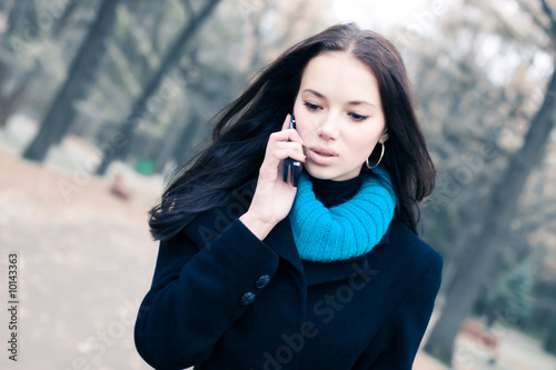 Young walking woman talking on mobile phone.