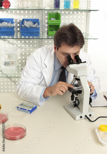 A scientist observes an object under a microscope in the lab