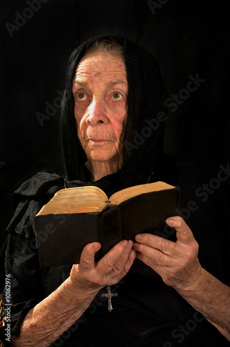 Old Catholic nun in prayer holding bible and rosary photo