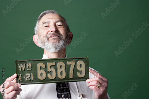 Senior man holding antique license plate