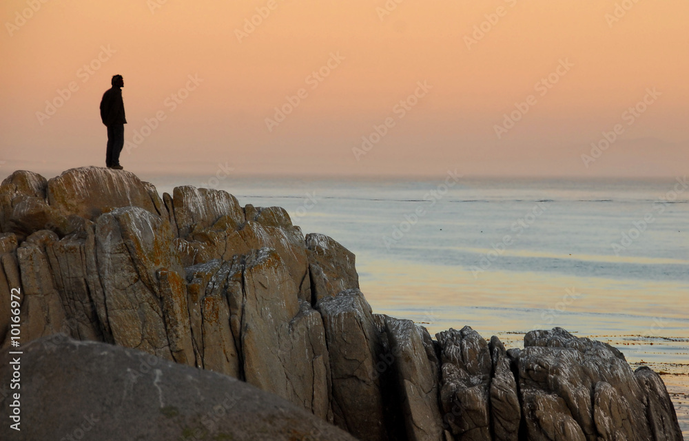 Man by himself on cliff overlooking sea