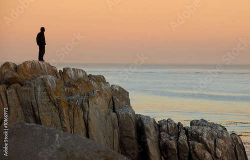 Man by himself on cliff overlooking sea