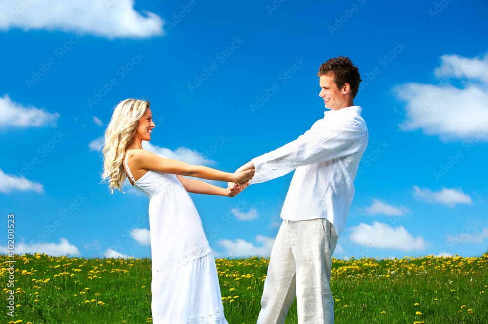 Young love couple smiling under blue sky.