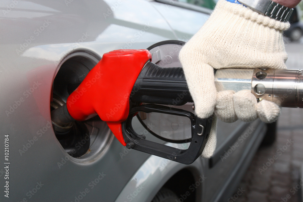 Bright red gas pump inserted into an automobile gasoline tank Bright red gas pump inserted into an automobile gasoline tank