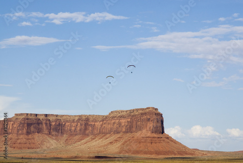 two powered paraglider pilots in flight over Monument Valley