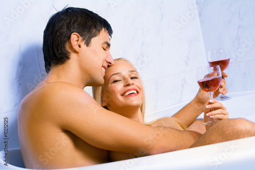 Young happy amorous couple celebrating with redwine at bathroom photo