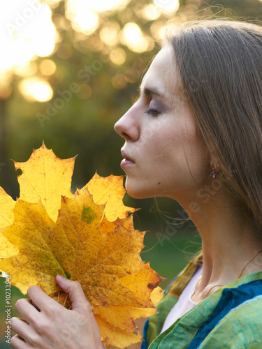 profile portrait of a beautiful girl with yellow maple leaves
