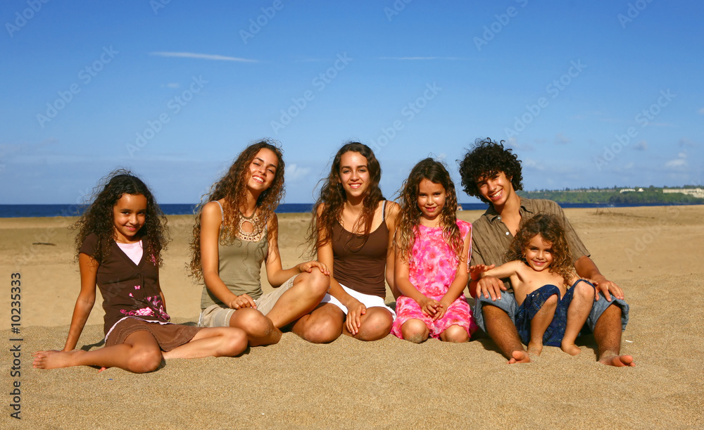 Happy Smiling Siblings Sitting on the Beach at Sunset Happy Smiling Siblings Sitting on the Beach at Sunset