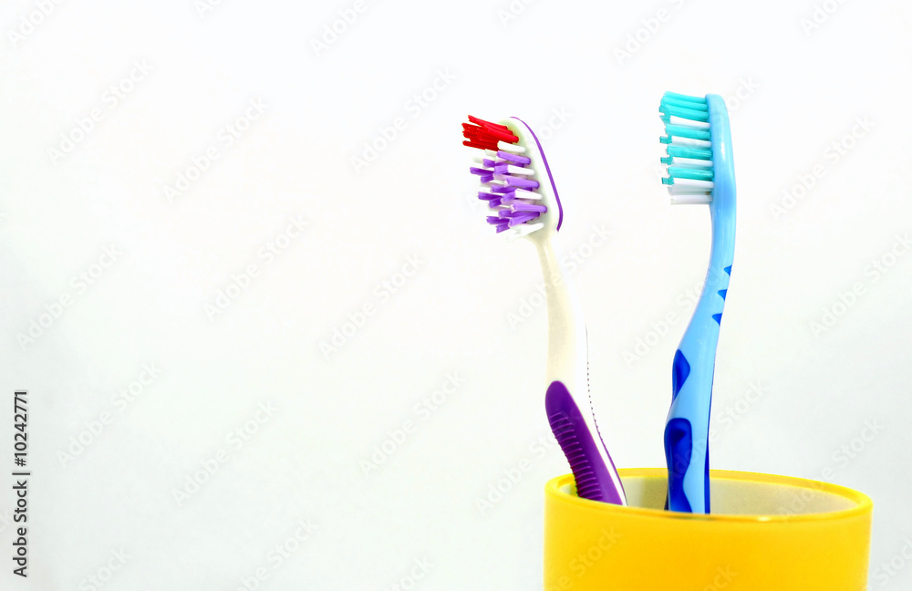 Two toothbrushes in yellow mug Two toothbrushes in yellow mug