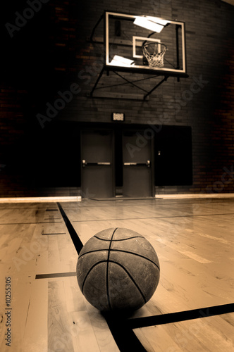 Basketball on court with hoop in the background © Lane Erickson