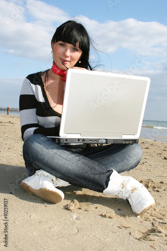 Young woman working with computer at the beach © zakharova ievgeniia