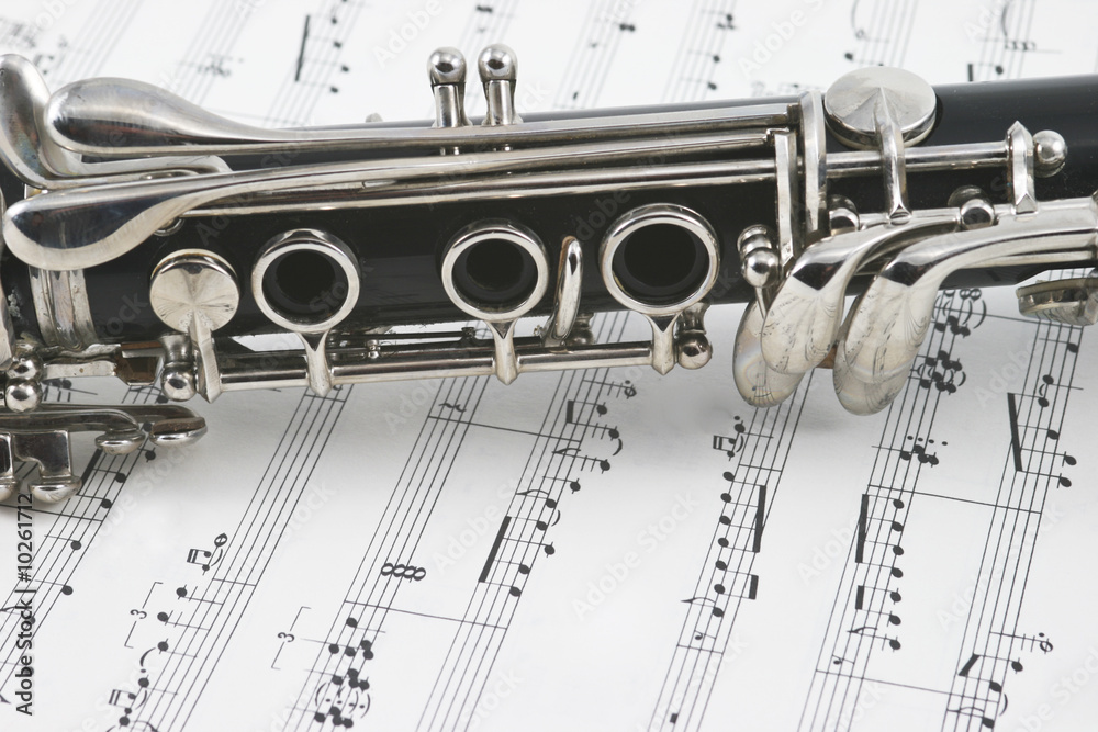 Middle of a clarinet with keys lying across some sheet music
