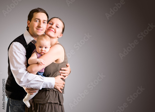 Studio picture of happy young parents and 4 months old baby
