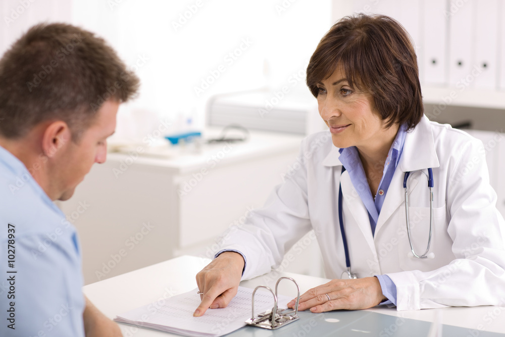 Smiling senior female doctor talking with male patient Smiling senior female doctor talking with male patient