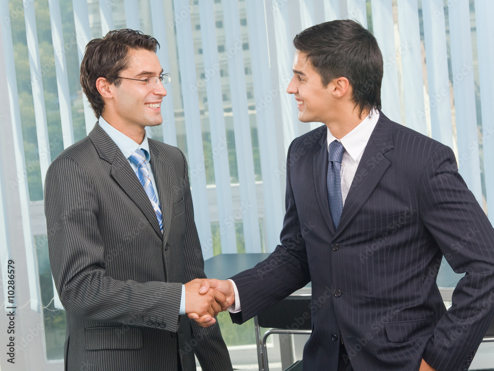 Two businesspeople cheering by handshake at office Two businesspeople cheering by handshake at office