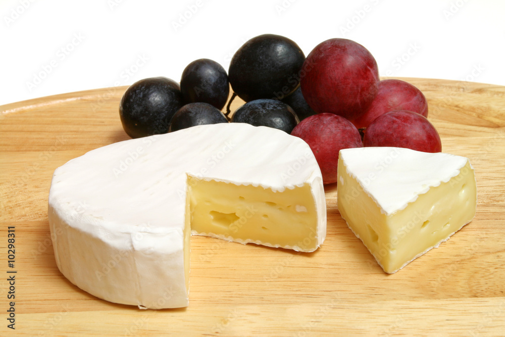 Camembert - soft cheese served on a wooden board with grapes