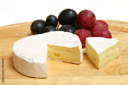 Camembert - soft cheese served on a wooden board with grapes
