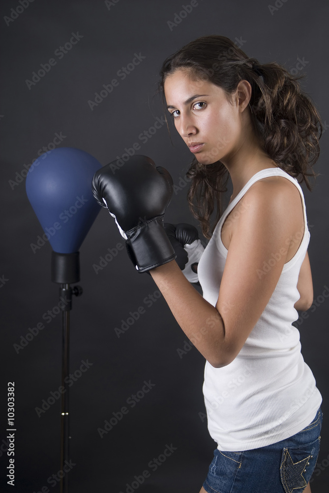 Young beauty woman boxer fighting with punch bag