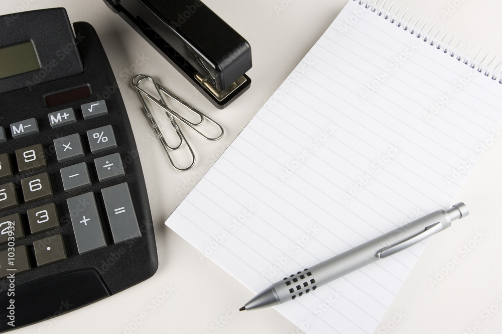 A desktop calculator, stapler,a blank pad and pen A desktop calculator, stapler,a blank pad and pen