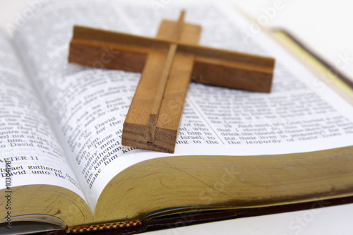 Wood cross laying on an opened Bible.