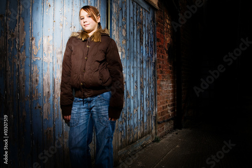 Teenage girl leaning against a door at night