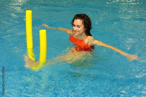 The young girl does exercise with aqua noodles