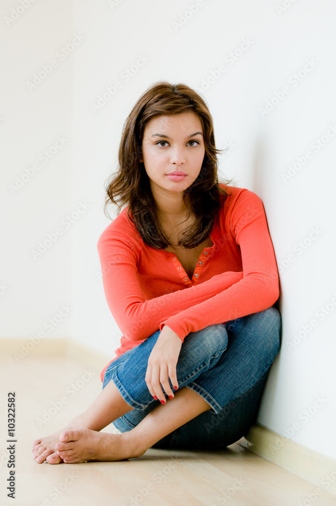 A lifestyle shot of a young woman sitting down on the floor
