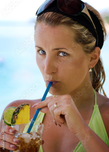 Beautiful young woman drinks on the beach drink