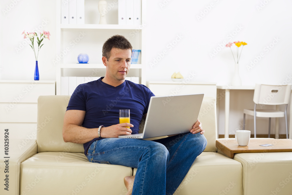 Man sitting on sofa at home and using laptop computer. Man sitting on sofa at home and using laptop computer.