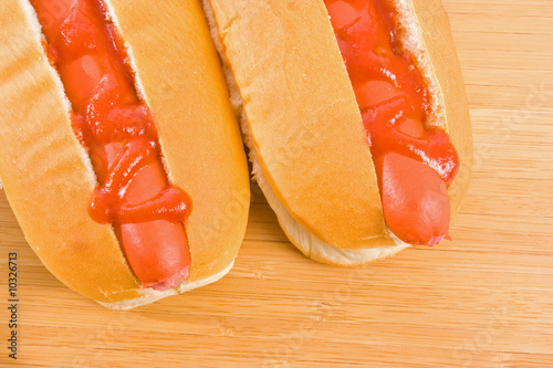 Close up of two hot dogs on wooden chopping board