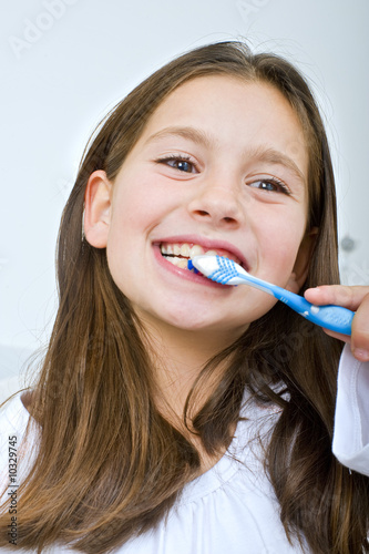 young girl brushing her teeth happily