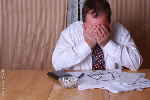 Man stresses out with bills stacking up on the kitchen table.