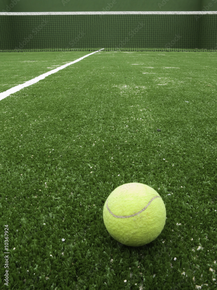 Tennis ball on synthetic grass of paddle court.
