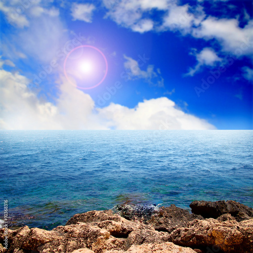 Sea landscape with cloudy sky and sun