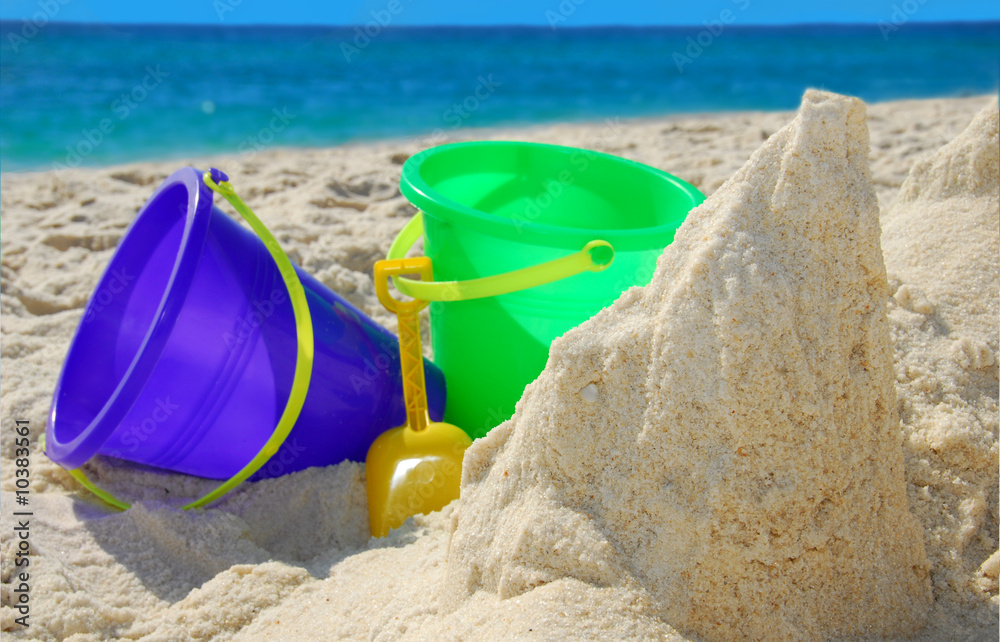 Sand buckets in beach sand next to gorgeous ocean water Sand buckets in beach sand next to gorgeous ocean water