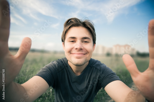 Young happy man stretching to the camera.