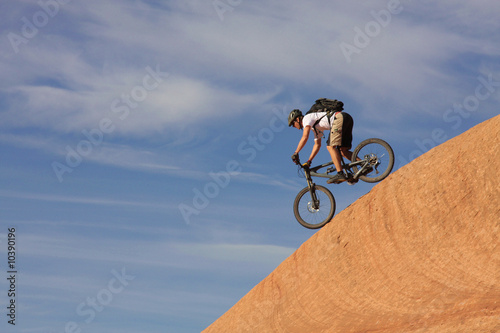 A fearless mountain biker drops down a steep trail.