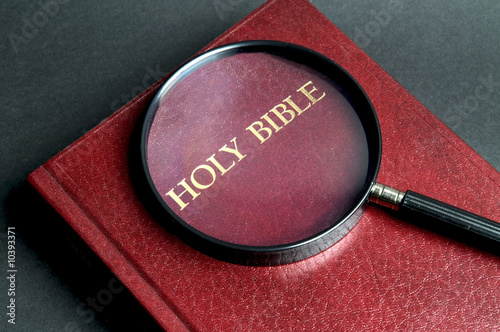 Loupe on a Bible. If  you're searching for answers, read it!