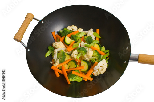 Fresh sliced vegetables in wok over white background.