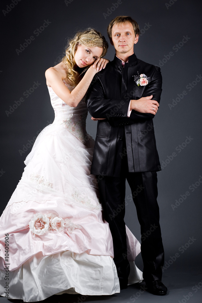 Bride and groom posing on gray studio background