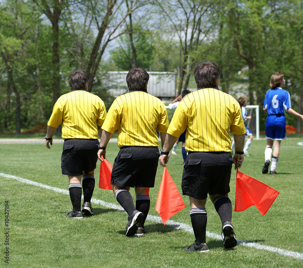 Fototapeta premium Triplet soccer side referee with red flag. Photo composition.