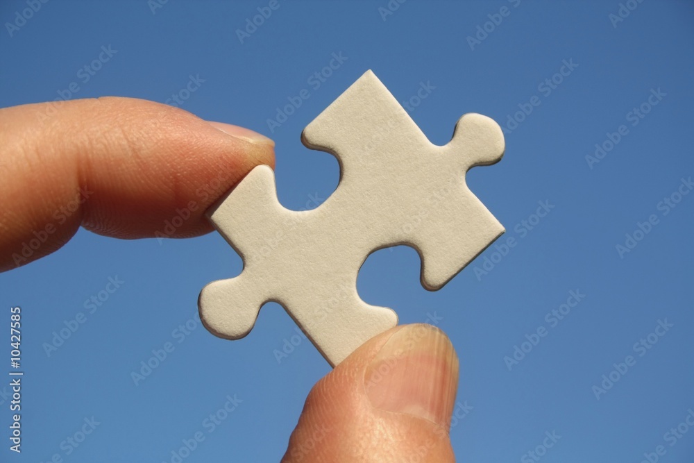 Pièce de puzzle blanche entre les doigts d'un homme Pièce de puzzle blanche entre les doigts d'un homme