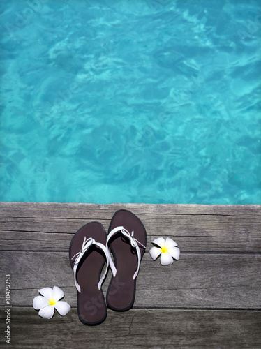 women sandals on a wooden floor with flowers near the water