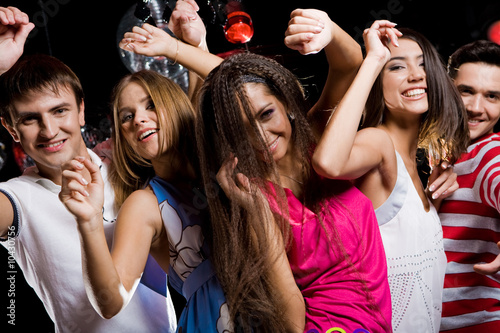 Company of cheerful teens enjoying themselves at disco