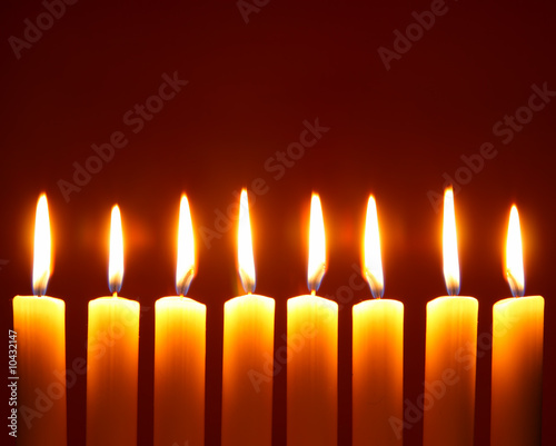 Eight alight candles close-up over red background