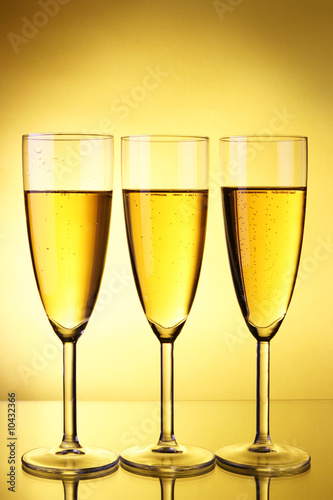 Three glasses of champagne over yellow background