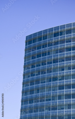 A blue glass office tower reflecting a clear blue sky