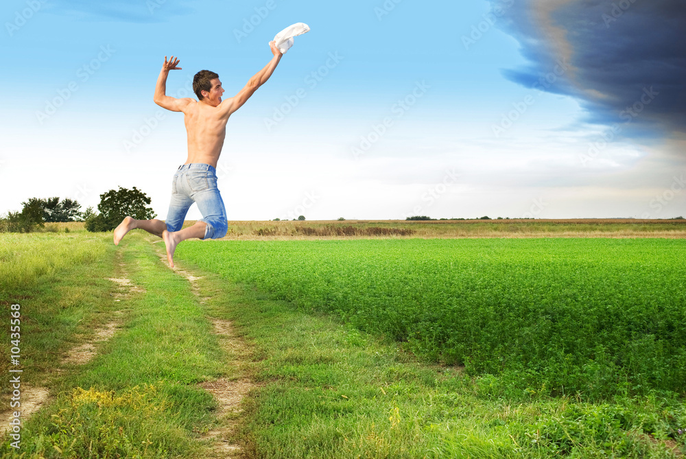 Young man jumping to meet clody skies through flat ground Young man jumping to meet clody skies through flat ground